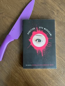 An image of the book Audition next to a large purple kitchen knife.